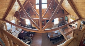 Ein Holzblock-Interieur mit hohen Decken, Holzbalken, einem Essbereich und einer Couch.