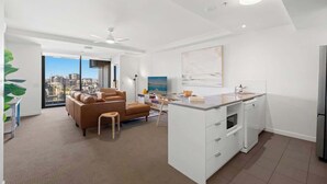 Un apartamento moderno con sala de estar, kitchenette y amplios ventanales con vistas a la ciudad.
