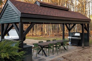 A covered outdoor dining area with a grill and seating. - Sleeps 18+| Hot Tub| Sauna | 7BR Mountain Retreat (Conway)