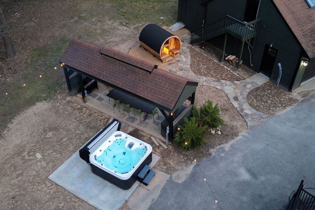 A hot tub, a covered seating area, and a building with a staircase.