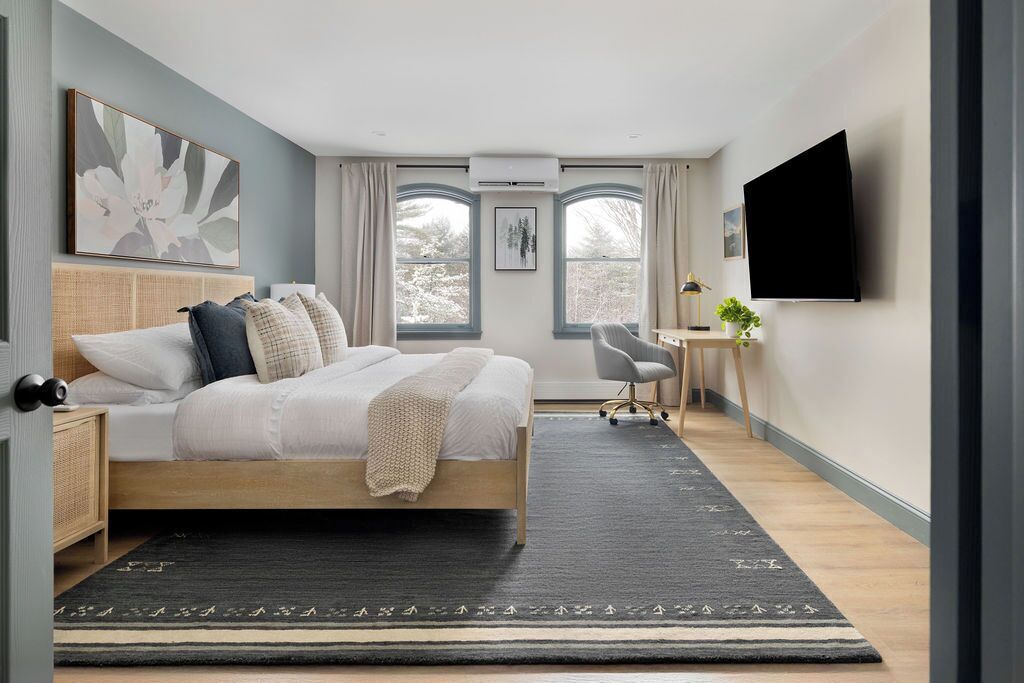 Un dormitorio moderno con cama, mesita de noche y escritorio con silla.