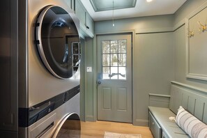 A laundry room with a built-in washer and dryer, a door with a window, and a bench with a cushion. - Sleeps 18+| Hot Tub| Sauna | 7BR Mountain Retreat (Conway)