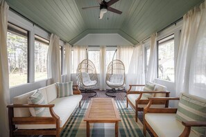 A room with a wooden ceiling, a ceiling fan, a sofa, two rocking chairs, a coffee table, and large windows with curtains. - Sleeps 18+| Hot Tub| Sauna | 7BR Mountain Retreat (Conway)
