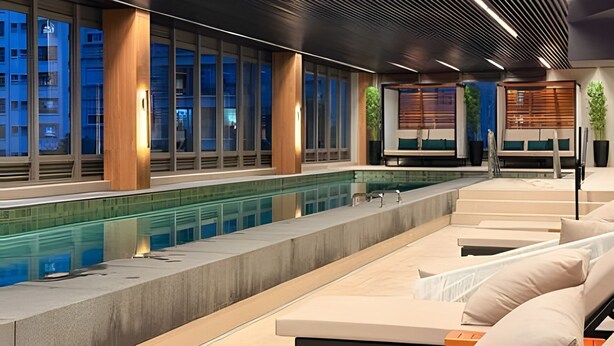 Et moderne poolområde indendørs med siddepladser og store vinduer.