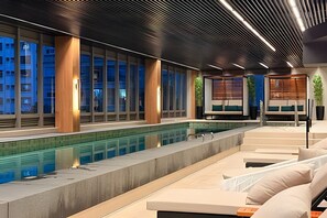 Un espace piscine intérieur moderne, doté de sièges et de grandes fenêtres.