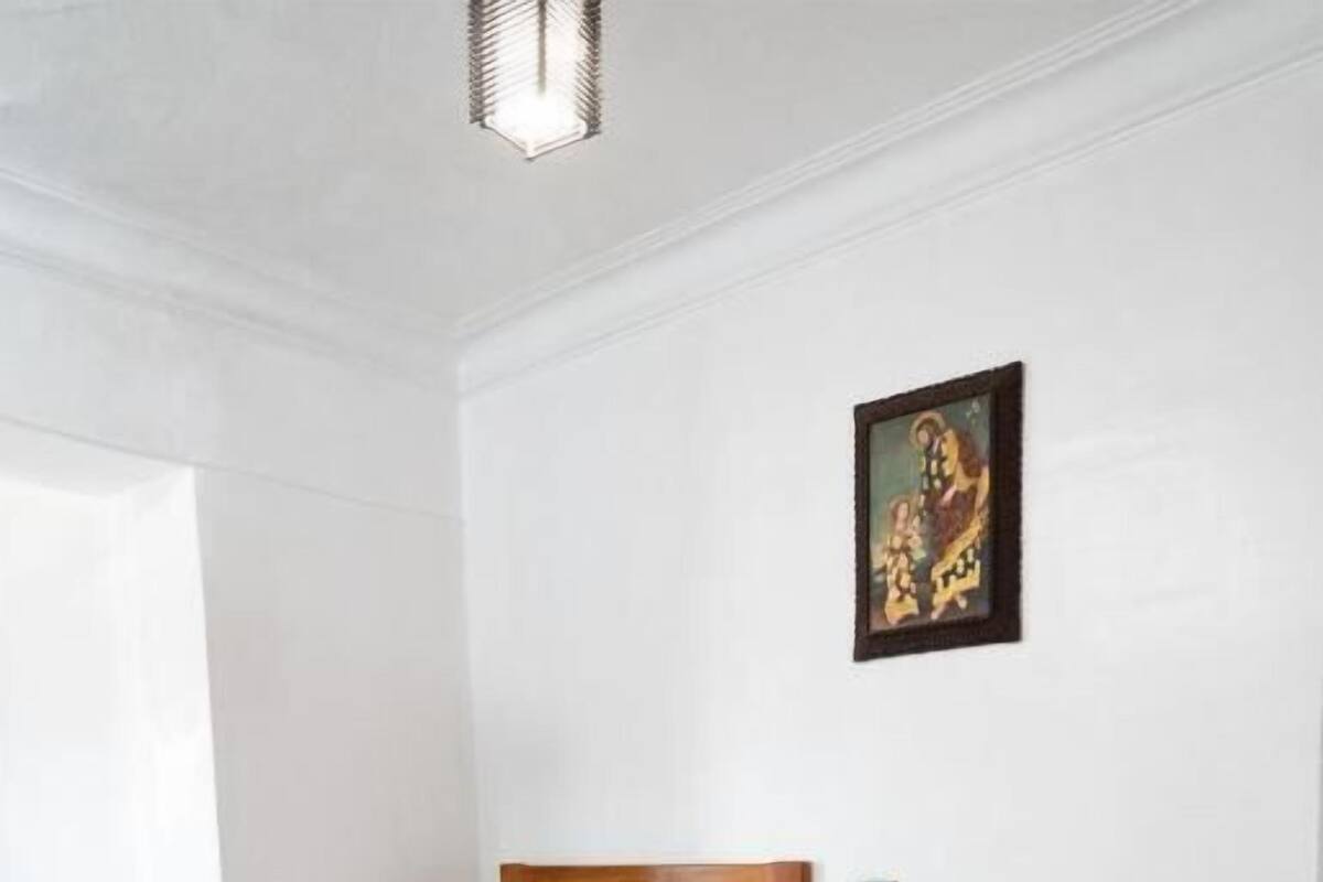 Habitación de hotel con dos camas de madera, ropa de cama roja y blanca, un cuadro en la pared y una alfombra roja.