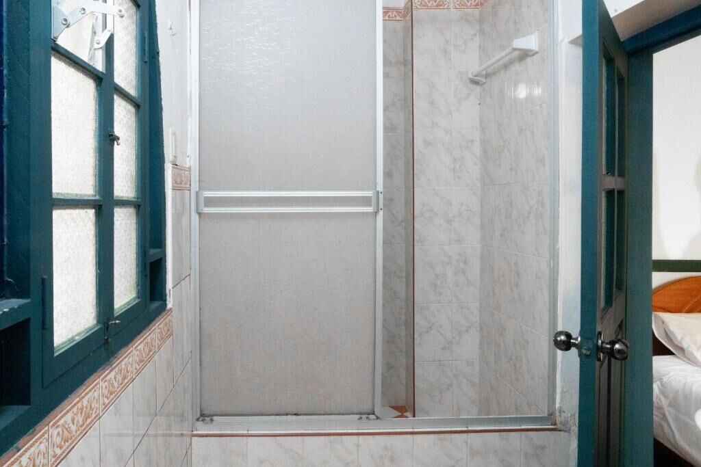 A bathroom with a shower, a door, and a window with a decorative frame.