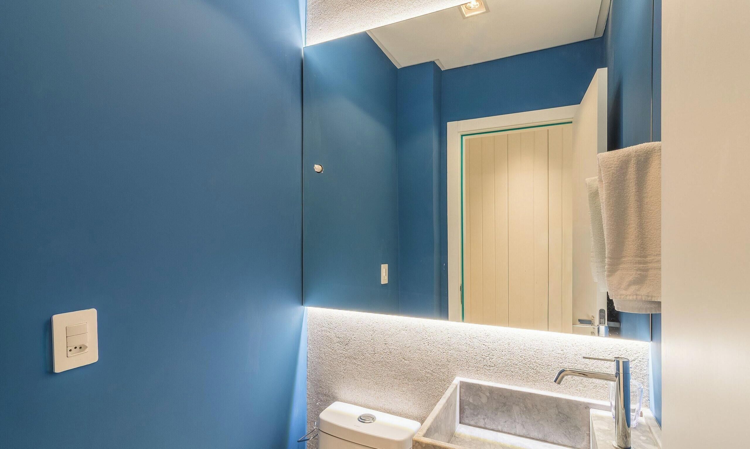 A bathroom with a blue wall, a white sink, and a mirror.