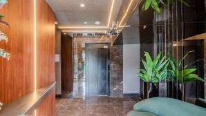 A modern lobby with a reception desk, a marble floor, and a green sofa. - Fully Equipped Stays Just Steps From the sea in Pereque Mtrs (Porto Belo)