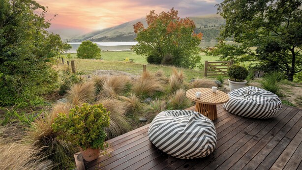 A wooden deck with two bean bags, a small round table, and a potted plant. - Overleigh Eco-Pod (Port Levy)
