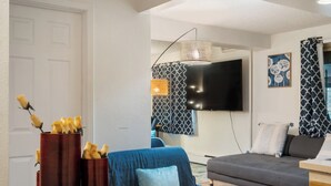 Ett modernt vardagsrum med ett matbord i trä, en soffa och en tv som är monterad på väggen.