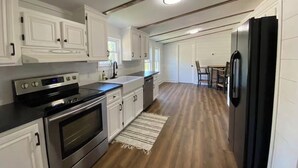 A kitchen with white cabinetry, stainless steel appliances, and a wooden floor.