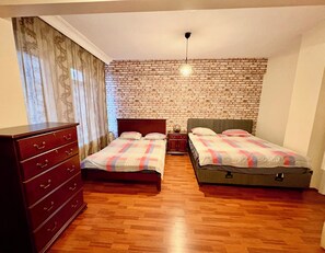 Ein Zimmer mit zwei Betten, einem Schminktisch, einer Ziegelwand und einer hängenden Leuchte.