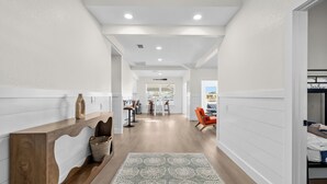 A modern hallway with a wooden console table, a patterned rug, and a view into a dining area with chairs and a table. - Newly remodeled 3-bedroom waterfront home in amazing Hernando Beach (Hernando Beach)