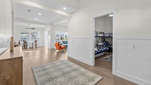A spacious room with a wooden floor, a patterned rug, a bunk bed, and a dining area with chairs and a table. - Newly remodeled 3-bedroom waterfront home in amazing Hernando Beach (Hernando Beach)