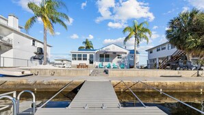A waterfront property with a dock, a house with a blue roof, and palm trees. - Newly remodeled 3-bedroom waterfront home in amazing Hernando Beach (Hernando Beach)