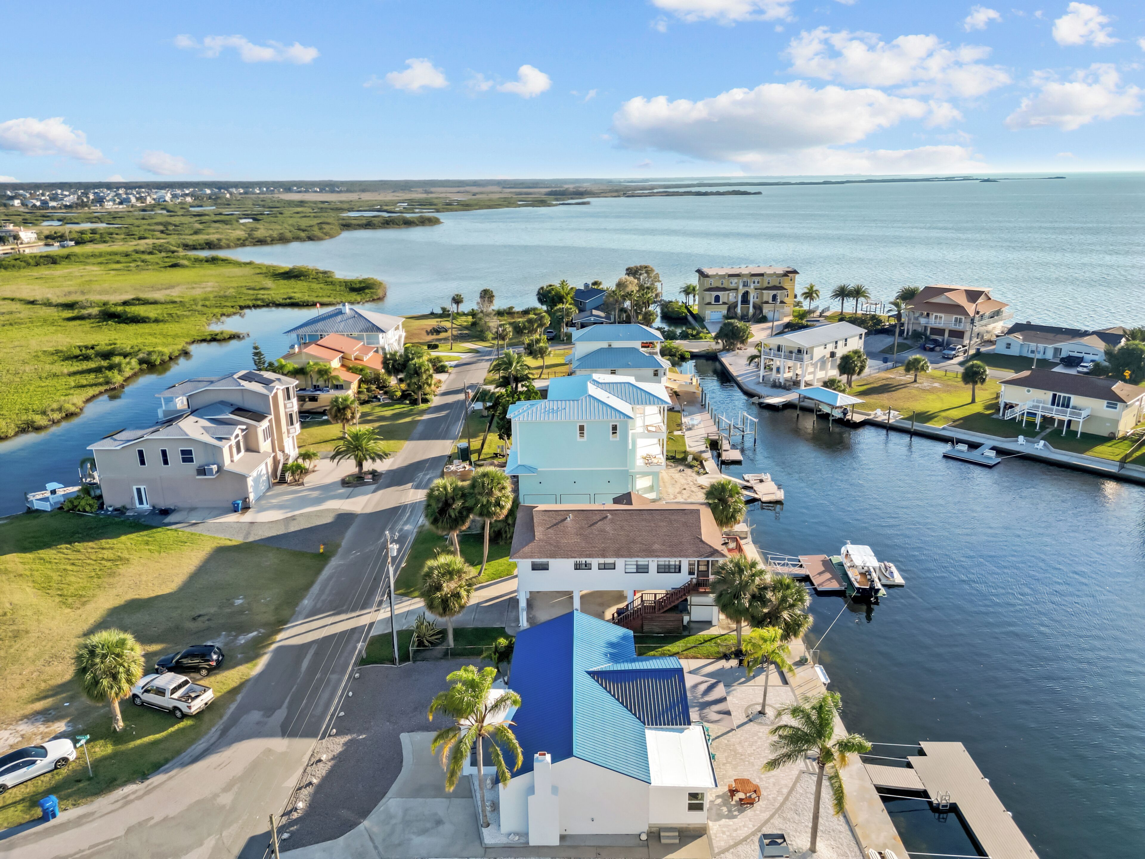 An aerial view of a coastal residential area with houses, a marina, and a river.