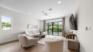 Un salon moderne avec un ensemble de canapés, une table basse et un téléviseur fixé au mur.