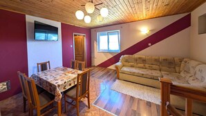 Un salon chaleureux avec un plafond en bois, une table à manger avec des chaises, un canapé et une fenêtre laissant entrer la lumière naturelle.