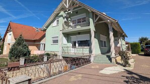 Une maison à deux étages avec un balcon, un toit rouge et une allée pavée.