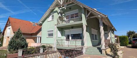 Una casa a due piani con un balcone, un tetto rosso e un vialetto lastricato.