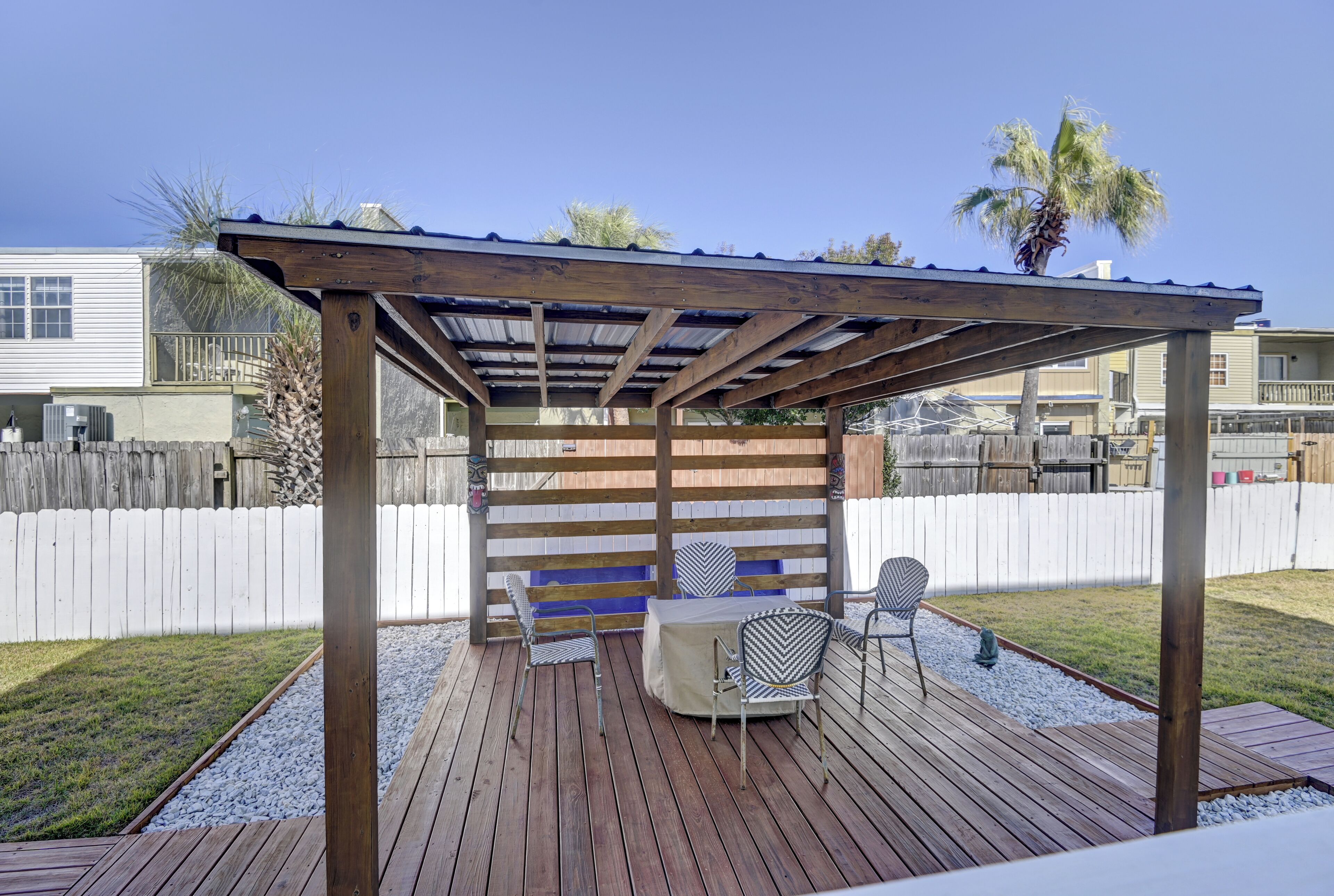 Un terrazzo in legno con una pergola, due sedie e un tavolo.