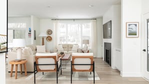 Un salon moderne comprenant un canapé, deux fauteuils, une table basse et une cheminée.
