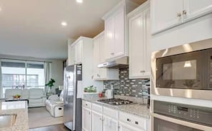 Una cocina moderna con armarios blancos, electrodomésticos de acero inoxidable y una isla central.