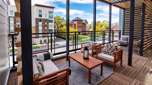Een balkon met houten vloer, een zithoek, een tafel en een lantaarn.