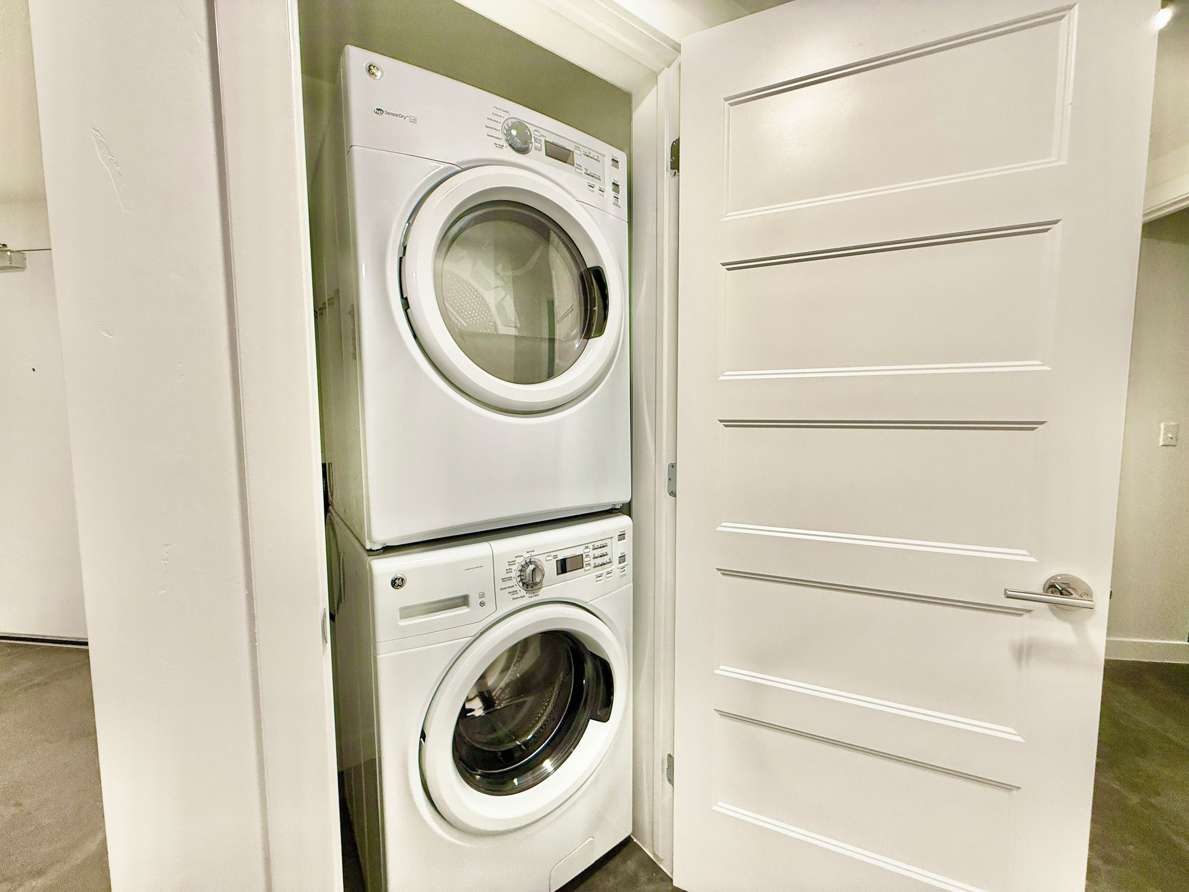 A laundry room with a front-loading washer and dryer stacked vertically.