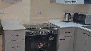 A compact kitchen with a stove, microwave, and cabinets.
