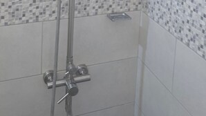 A shower with a handheld showerhead and a wall-mounted control panel.