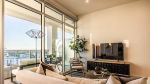 Una sala de estar moderna con un sofá, un televisor y un comedor con sillas y una mesa.