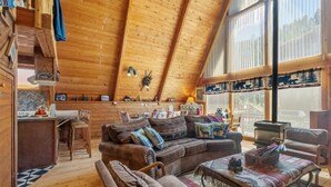 A cozy cabin interior with a wooden ceiling, a fireplace, a dining area, and a living room furnished with sofas and a coffee table. - New Listing! Ski In Ski Out! "HH Creeks Legacy" Updated Cabin-In Town-Close to Copper Chairlift (Red River)