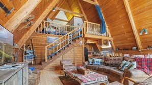 A log cabin interior with a loft bedroom, a dining area, and a living room furnished with leather sofas and a fireplace. - New Listing! Ski In Ski Out! "HH Creeks Legacy" Updated Cabin-In Town-Close to Copper Chairlift (Red River)