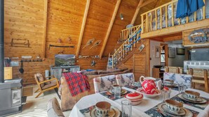 A wooden cabin interior with a dining area, a fireplace, and a loft with a staircase. - New Listing! Ski In Ski Out! "HH Creeks Legacy" Updated Cabin-In Town-Close to Copper Chairlift (Red River)