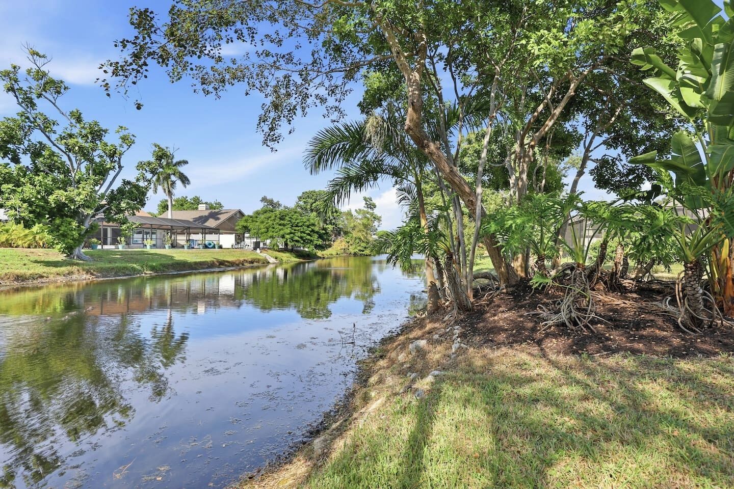 A serene lakeside setting with a house and lush greenery.