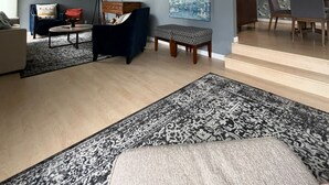 Ein modernes Wohnzimmer mit einer Couch, einem Couchtisch und einem gemusterten Teppich.