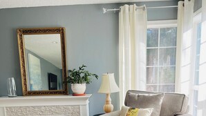 Ein Wohnzimmer mit Sofa, Hocker, Kamin, Spiegel und einer Topfpflanze.