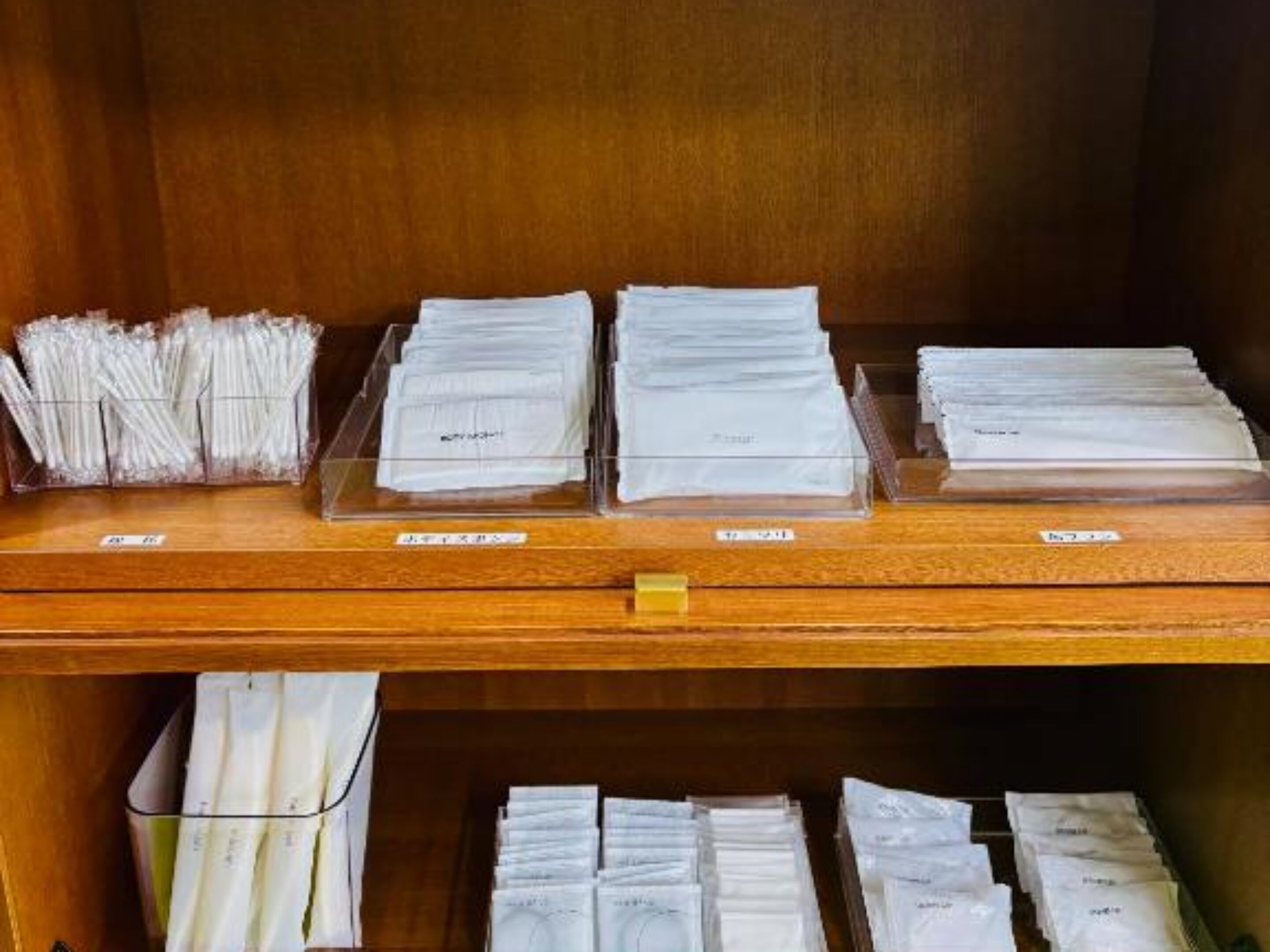 A wooden counter with multiple trays of neatly stacked white envelopes, each labeled with names.