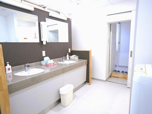 Un baño moderno con dos lavamanos, un espejo grande y un cesto de basura.