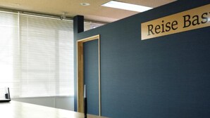 A reception desk with a sign reading "Reise Basis" and a door to the left. - HOTEL Reise Basis (Senboku)