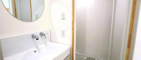 A bathroom with a white sink, a mirror, and a shower area.