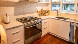Una cocina con muebles blancos, una estufa de acero inoxidable y una ventana con vistas al exterior.