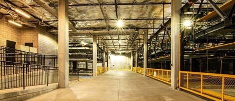 An indoor parking garage with concrete floors, metal railings, and exposed ductwork.