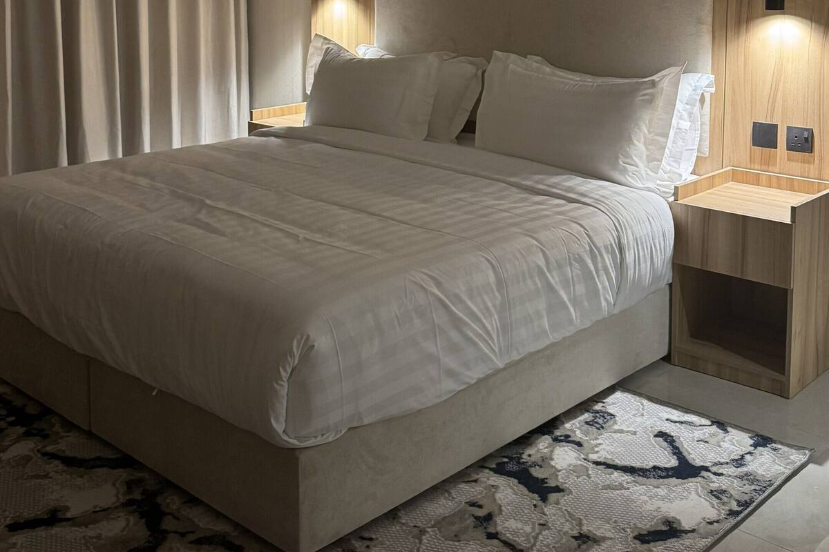Ein modernes Schlafzimmer mit einem großen Bett, Nachttischen, einer Klimaanlage und einem gemusterten Teppich.