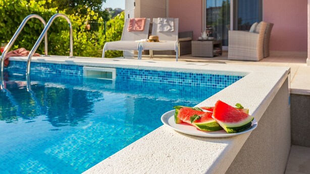 A swimming pool with a tiled edge and a plate of watermelon slices on the side. - in Stobreč mit privatem Pool by Interhome (Split/Stobreč)