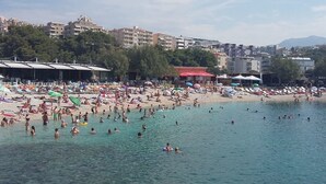 A crowded beach with people swimming and sunbathing, surrounded by buildings and trees. - Wohnung in Žnjan by Interhome (Dragovode)