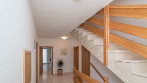 A hallway with a wooden staircase, a potted plant, and a door leading to another room. - Apartment mit zwei Schlafzimmern und eigenem Balkon by Interhome (Trogir/Okrug Donji)