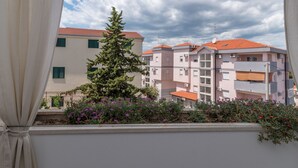 A view through a window of a building with balconies and a tree in the foreground. - Apartment mit zwei Schlafzimmern und eigenem Balkon by Interhome (Trogir/Okrug Donji)